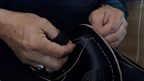 Making hand stitches in stitch-down construction of Martens Boots